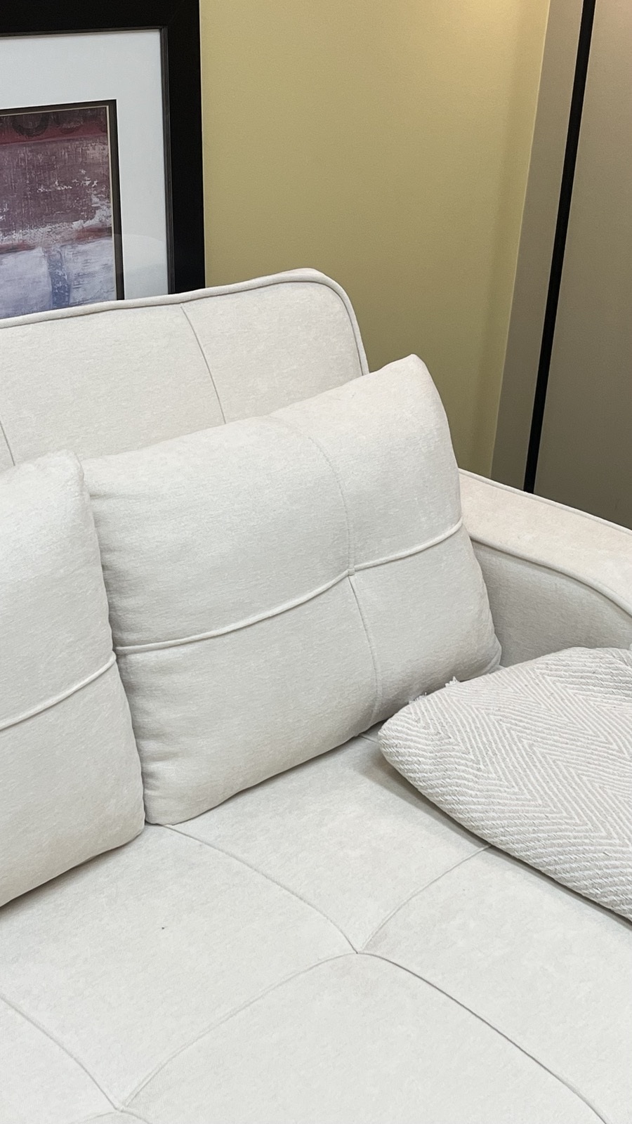 A close view of the cream sofa and cushion in Veronica’s office